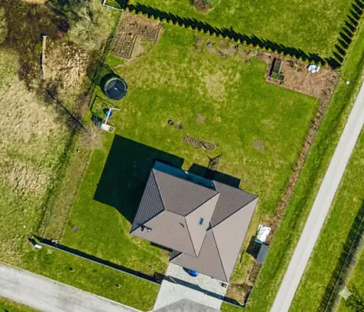 Aerial satellite view of a residential backyard with garden beds and lawn